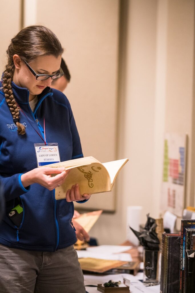 Starsha examines a book for sale at Mythmoot