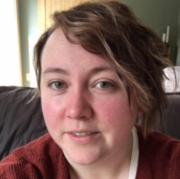 A lovely woman with rosy cheeks and swept hair smiling gently